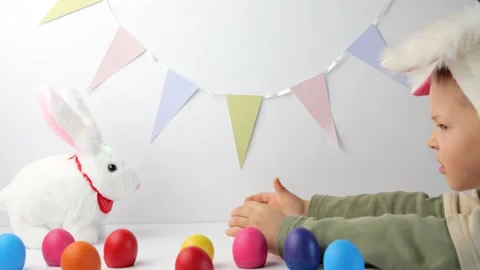 Boy in rabbit ears on head play with cute toy bunny Stock Footage 148864597