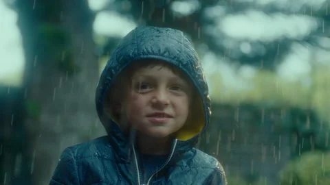 Boy in a rain coat standing in the rain Stock Footage 279152573