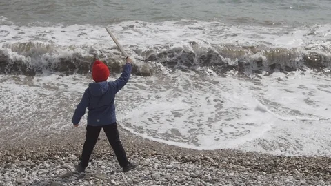 Boy with a raised sword in hand in the background against the waves Stock Footage 88441895