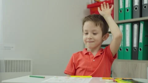 Boy raises his hand during a lesson in classroom and the teacher approaches him. Vídeos de archivo 261520896