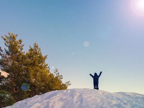 Boy raises his hands while standing on top of rocks. winter. snow rocks Stock Photos