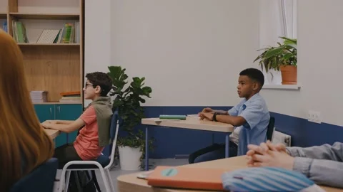 Boy raising a hand to ask a question, children attentively listen teacher Stock Footage 162740162