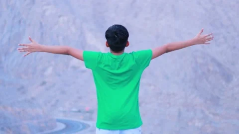 Boy raising his hands to express his happiness in a mountain wearing in green Stock Footage 159659328