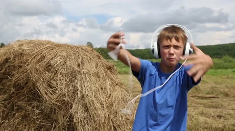 Boy rapping with headphones on the background of haystack outdoors Stock Footage 53416820