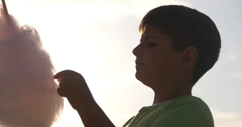 The boy in the rays of the sunset has sweet cotton Stock Footage 92032935