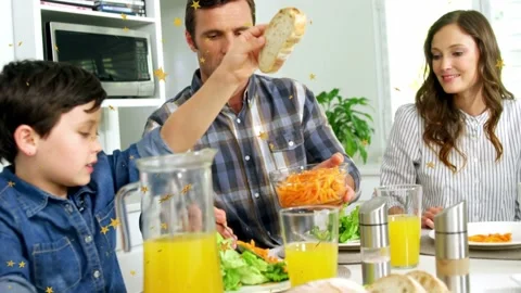 Boy reaching for bread causing man scooping carrots, family sharing food at Stock Footage 332705089