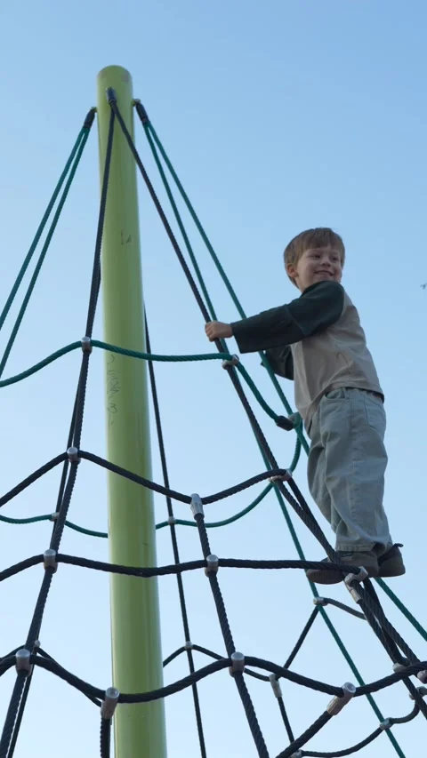 Boy reaching the top of climbing structure. Child facing height challenge on Stock Footage 329277820