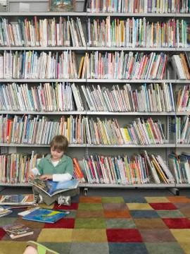 Boy Reading Book In Library Stock Photos