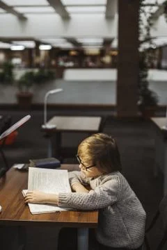 The boy is reading a book in the library 写真素材