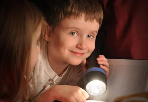 Boy reading book at night with flashlight Stock Photos