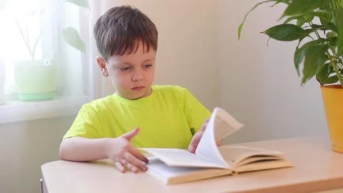 The boy is reading a book at the table . Children's books. Extracurricular Stock Footage 165238177