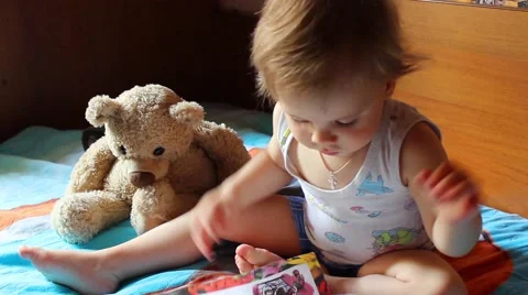 Boy reading a book, a teddy bear beside him 動画素材 62473956