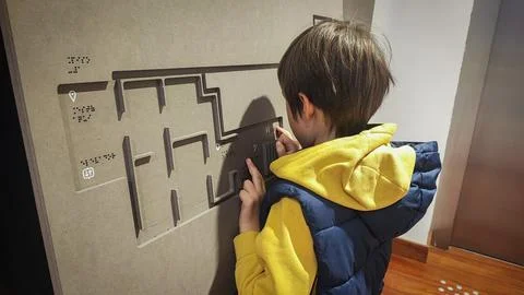 A boy reading the evacuation plan on the wall in braille. Close-up of a child Foto stock