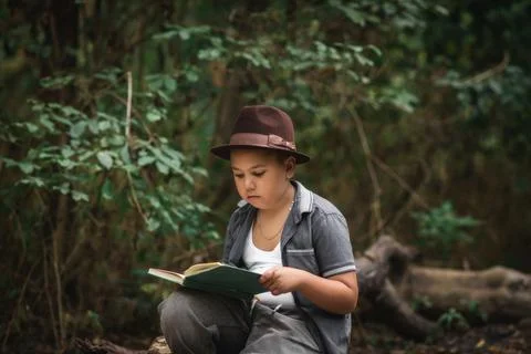 Boy reading an open book sitting in a forest. Foto stock