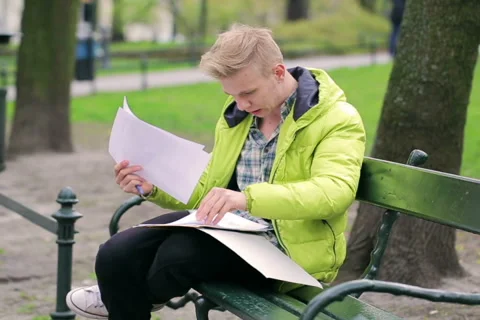 Boy reading papers and smiling to the camera in the park Stock-Footage 49471139