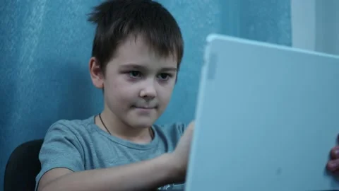 The boy reads on a white tablet sitting at the table Stock Footage 144263005