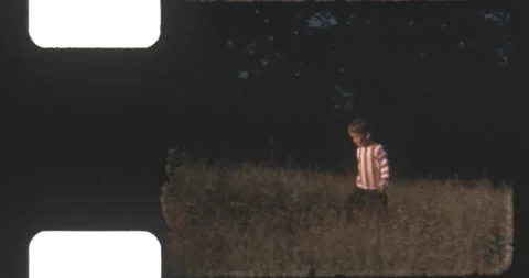 Boy in red and white striped sweater walking in the field Stock Footage 206028036