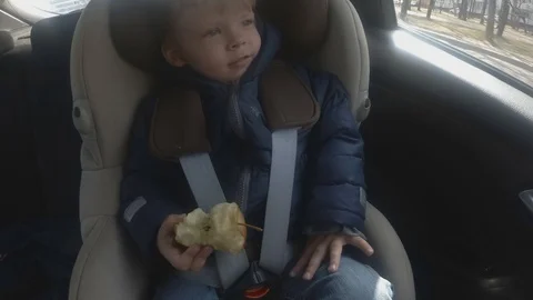 Boy with red apple sitting in car. Soft focus. Stock Footage 106861715