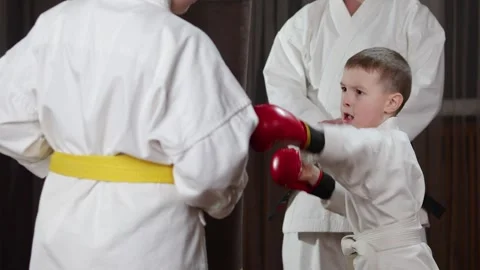 A boy in red arm pads performs punches on a large hanging machine Stock Footage 279444525