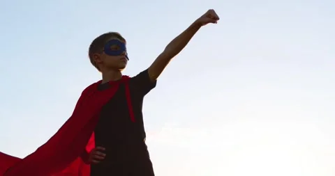 Boy in red cape imagines himself superhero at sunset. Child plays and dreams of Stock Footage 330860839