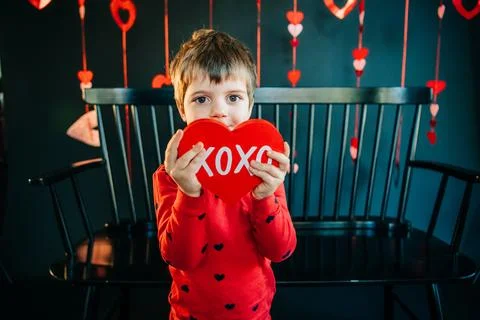 Boy in red heart-pattern pajamas holding a red "XOXO" heart prop Stock Photos