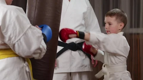 A boy in red pads on his hands trains punches on a large simulator Stock-Footage 279444517