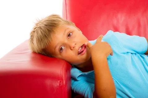 Boy on red sofa Stock Photos