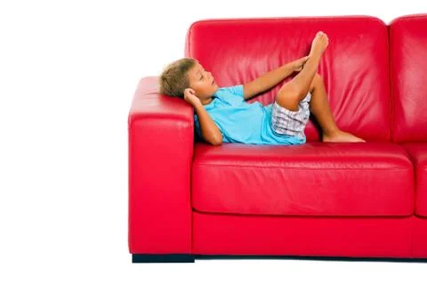 Boy on red sofa Stock Photos