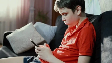Boy in a Red T-Shirt Is Having fun with his Phone, Teenager with a Smartphone Stock Footage 153319837