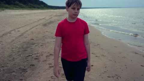 Boy in Red T-Shirt Walking Barefoot Along Sandy Beach Shore 库存影片 340581266