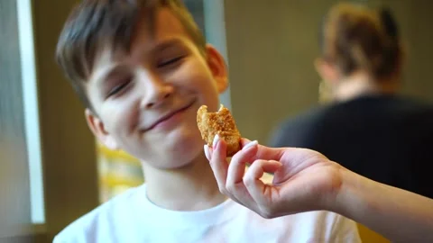 The boy refuses to eat the chicken nuggets his mother hands him. Stock Footage 248377621