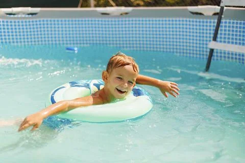Boy relaxing on inflatable ring floating in pool have fun during summer vacation Stock Photos