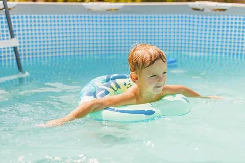 Boy relaxing on inflatable ring floating in pool have fun during summer vacation Stock Photos