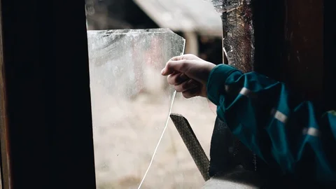 The boy removes the broken glass from the window frame. Abandoned house Stock Footage 128016578