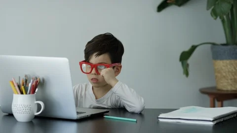Boy removing glasses while using laptop at home Stock Footage 106316454