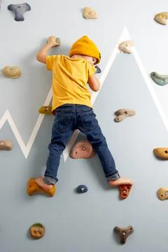 The boy resolutely climbs up the climbing wall Stock Photos