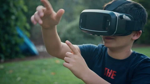 Boy responding with hand movements while using a virtual reality headset ou.. Video stock 275289380
