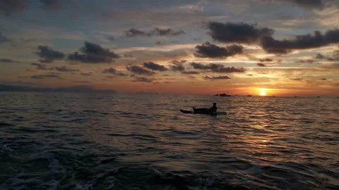 Boy resting and watching the sunset on his paddle surf Stock Footage 135744688