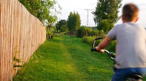 Boy rides a bicycle through the village Stock Footage 59673580