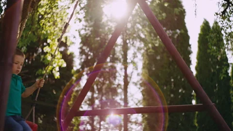 The boy rides on a children's swing. Stock Footage 195097067