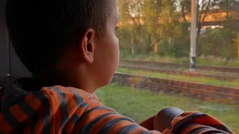The boy rides in a train car and looks out the window. Stock Footage 311973954
