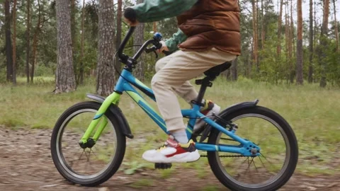 Boy riding bicycle fast through forest greenery Stock Footage 315756554