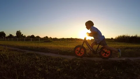 Boy is riding the bike while summer sunset. Kid rides on the bike outdoors. Stock Footage 105060432