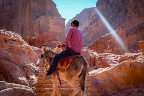 A boy riding up on a donkey in a canyon made of sandstone Stock Photos