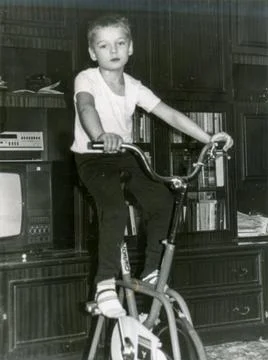 Boy riding exercise bike in soviet living room 1980s Stock Photos