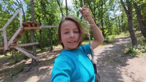Boy riding fast on a zip line through the forest, holding a camera in front of Stock Footage 313537809