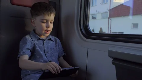 The boy is riding in the train, playing games on the tablet Stock Footage 89574630
