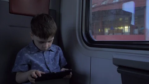 The boy is riding in the train, playing games on the tablet Stock Footage 89575418
