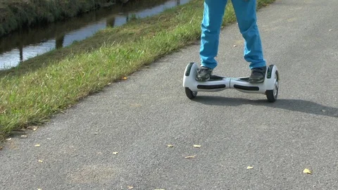 Boy riding on a white hoverboard, on a small road in the countryside Stock Footage 103596194