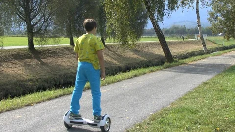 Boy riding on a white hoverboard, on a small road in the countryside Stock Footage 103598966